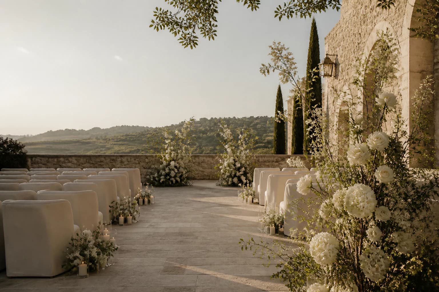 An intimate stone courtyard prepared for a wedding ceremony with ivory flowers
